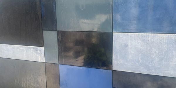 A wall made of rectangular tiles in shades of blue, gray, and black.