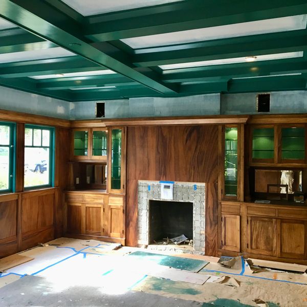 Room under renovation with wooden paneling and a fireplace.