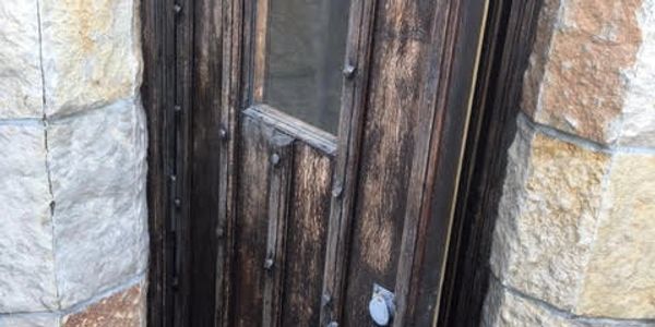 Old wooden door with metal studs set in a stone wall.