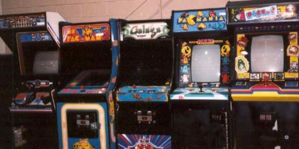 A row of vintage arcade game machines including Pac-Man and Galaga.