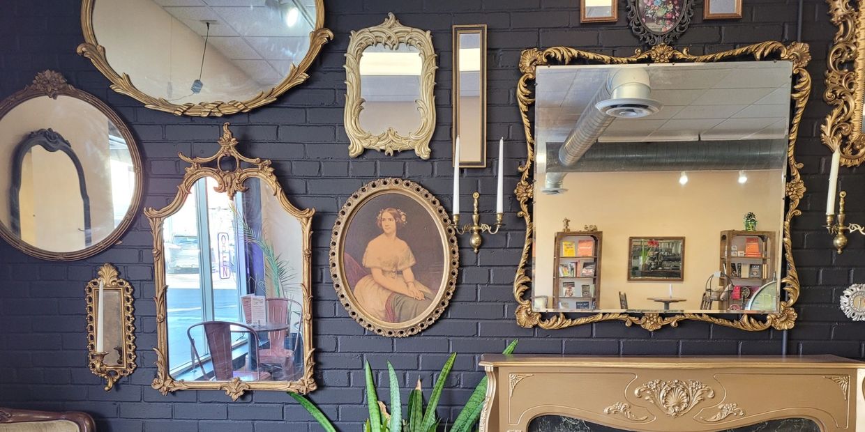 Elegant vintage mirrors and portrait on a dark brick wall enhance a cozy room.