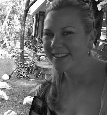 Smiling woman outdoors in a garden setting.
