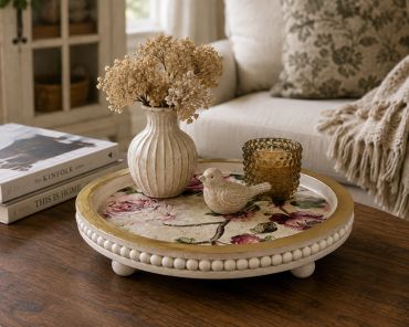 Decorative tray with bird figurine and dried flowers on table.