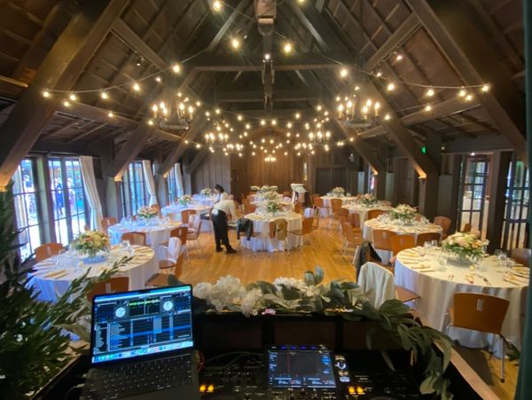 Elegant wedding reception setup with round tables and floral centerpieces under warm string lights.