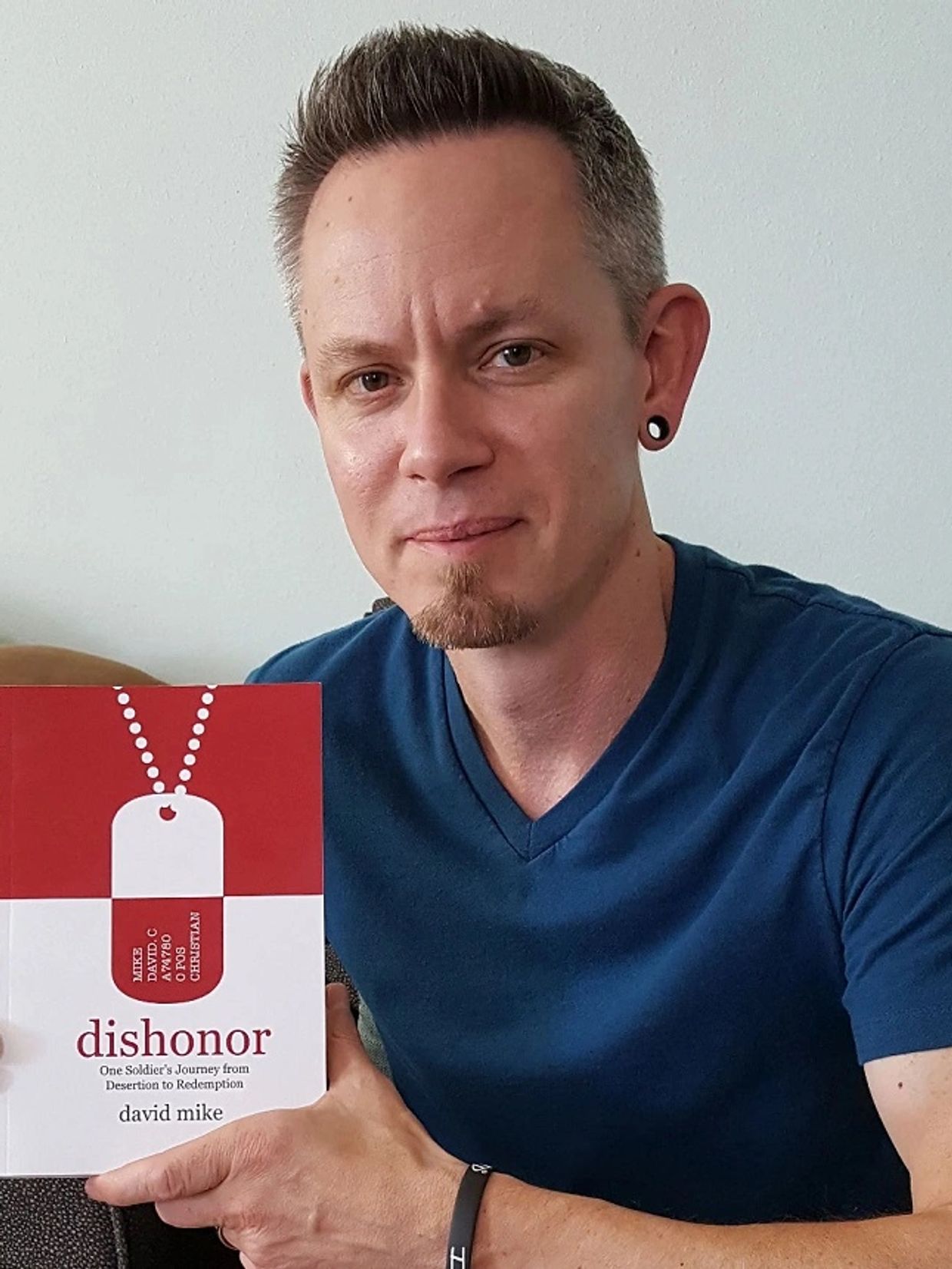 Man holding a book titled 'dishonor' by David Mike.