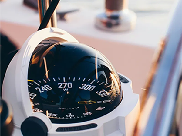 Close-up of a marine compass on a boat reflecting the sunset.
