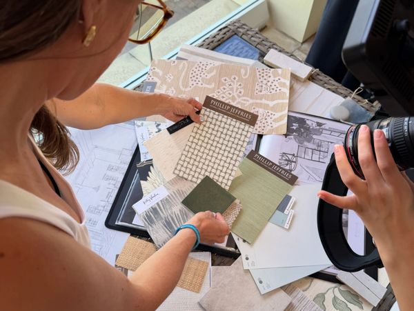 Person selecting fabric and wallpaper samples for interior design.