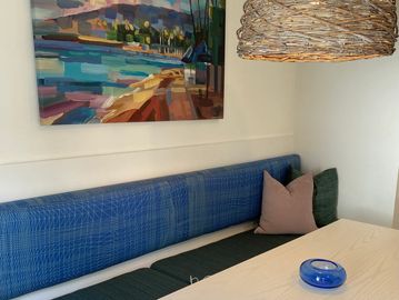 Cozy dining nook with blue bench and artwork.