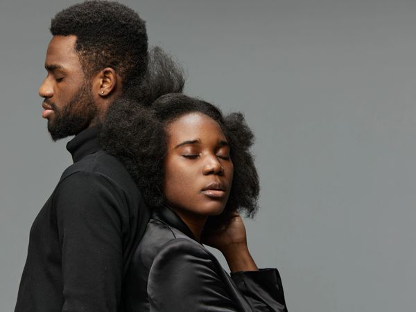 Two people with eyes closed, leaning on each other in peaceful embrace.
