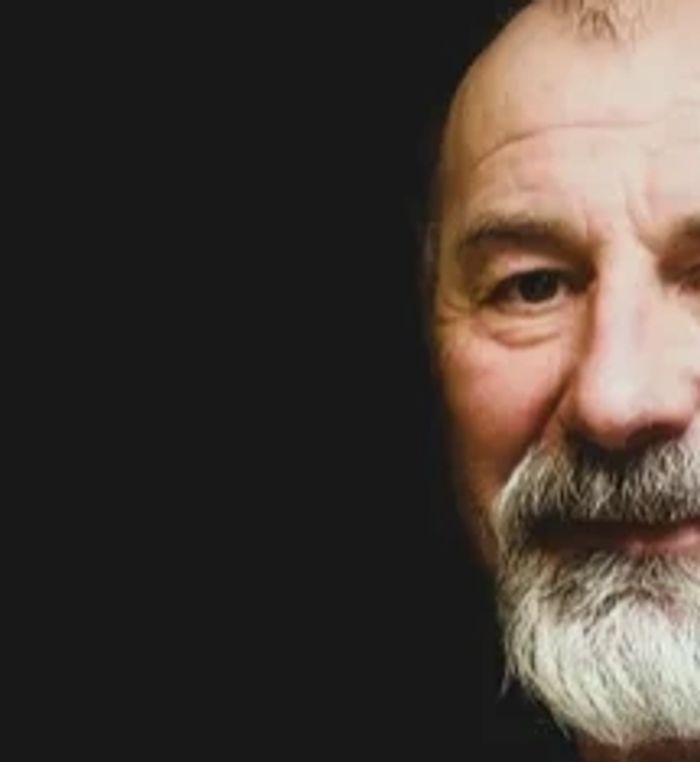 Portrait of an elderly man with a white beard against a black background.