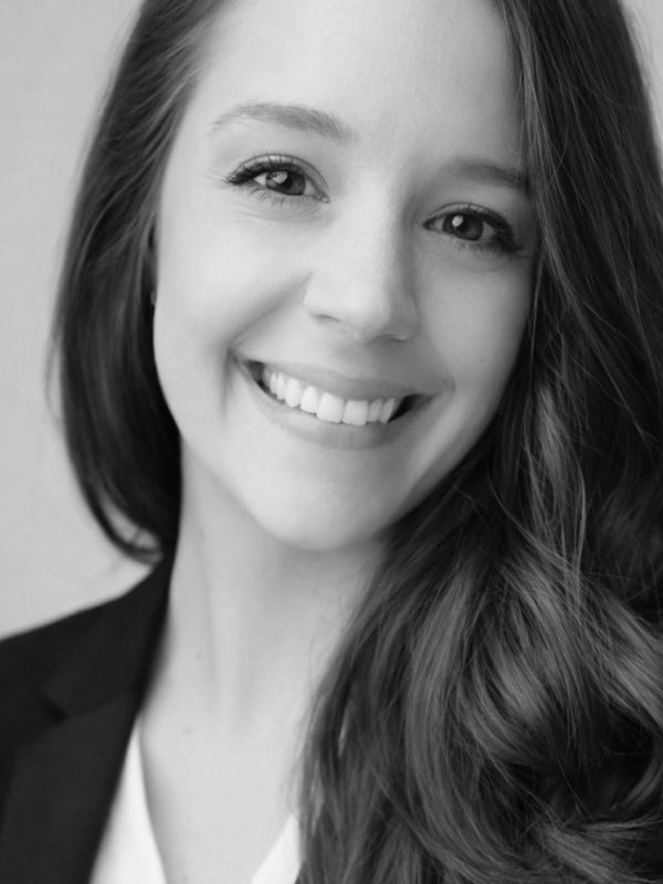 Close-up portrait of a smiling woman with long hair in black and white.