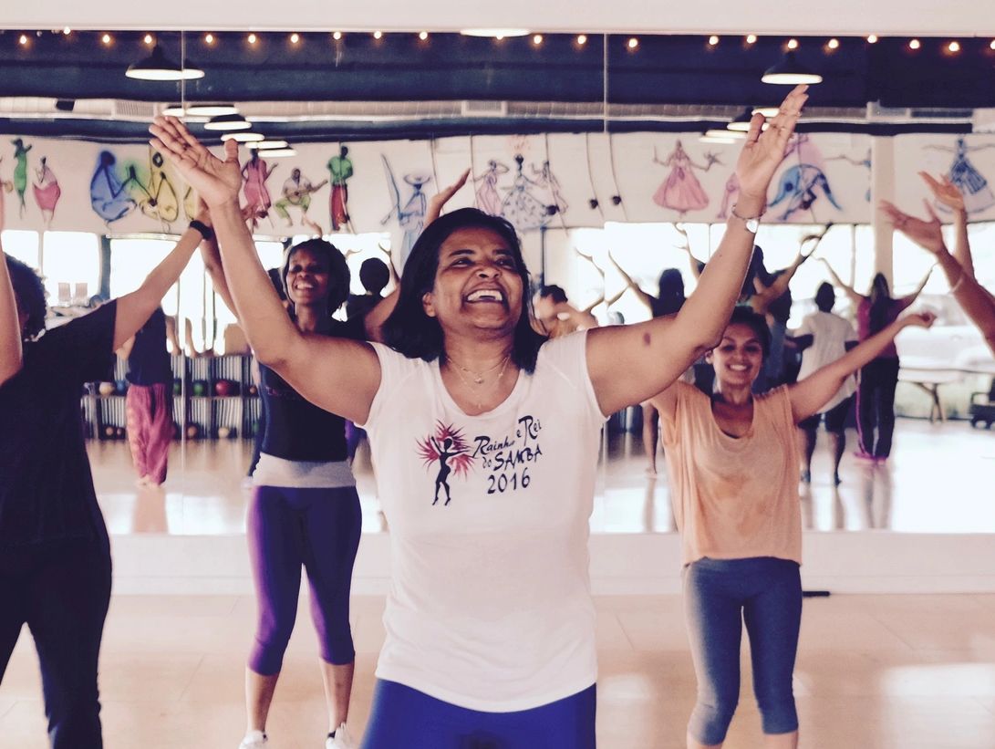 Happy women dancing in a studio with arms raised.
