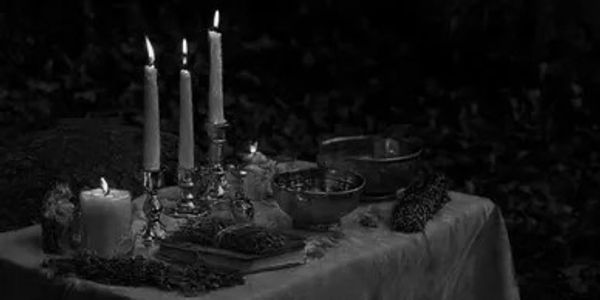 Three lit white candles on a dark ritual altar.