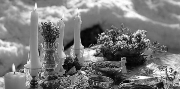 Altar with singing bowl, herbs, and candles on a table.