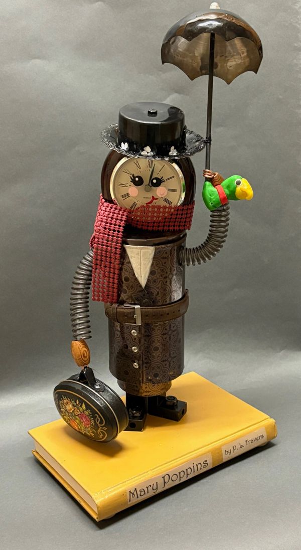 A whimsical Mary Poppins figure made from a clock and metal parts, standing on a book.