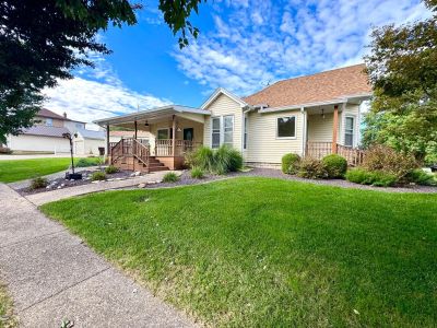 A cozy suburban house with a wooden porch under a blue sky.