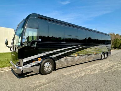 Sleek black luxury tour bus with silver accents parked on a street.
