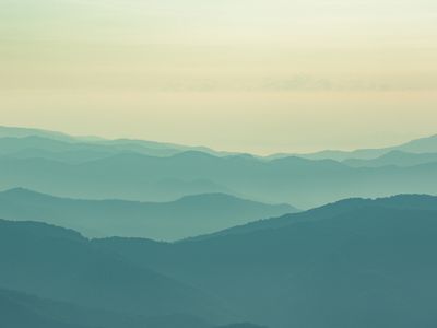 Layers of misty mountains under a pale sky.
