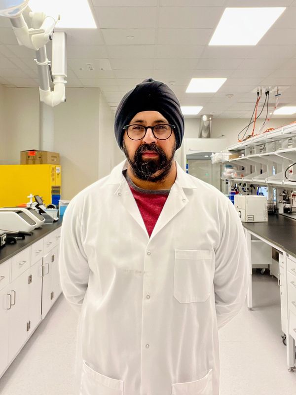 Man in lab coat and turban standing in a modern laboratory.