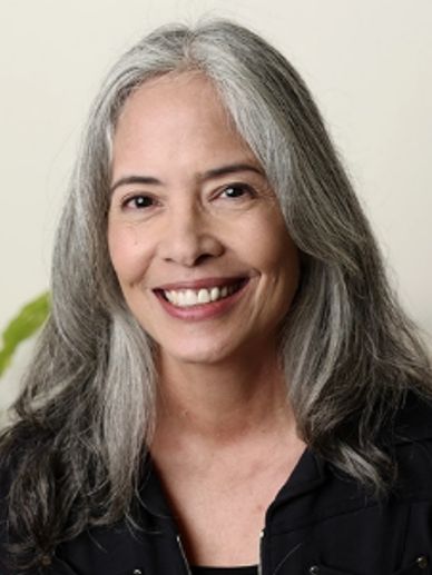 Smiling woman with long gray hair.