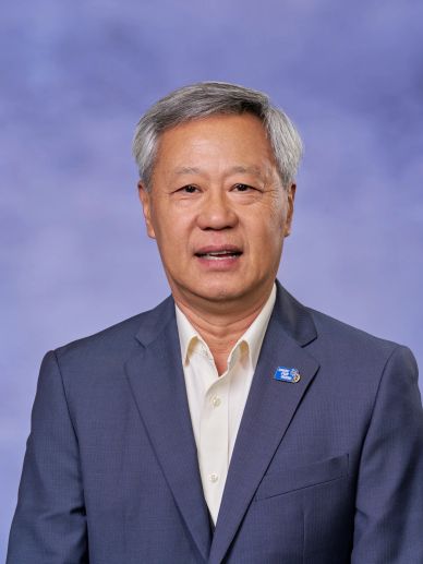 Portrait of a man in a blue suit against a blue background.