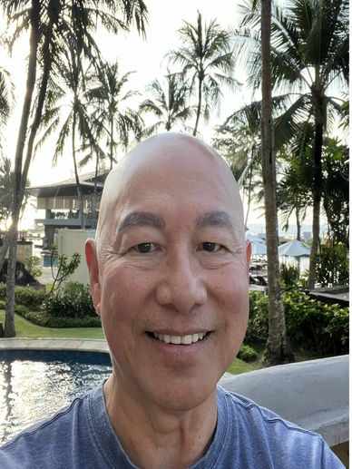 Smiling man in a tropical outdoor setting.