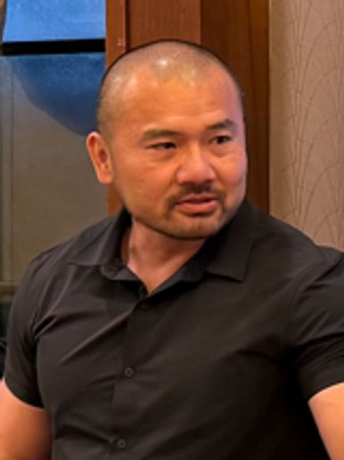 Man in a black shirt looking to his side.