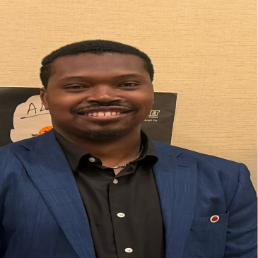 Smiling man in a blue suit jacket and black shirt.
