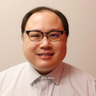 Smiling man wearing glasses and a checkered shirt.