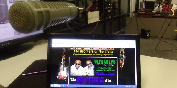 Podcast setup with a microphone and a laptop screen showing 'The Brothers of the Blues'.