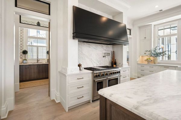 Modern kitchen with marble countertops and a large black stove hood.