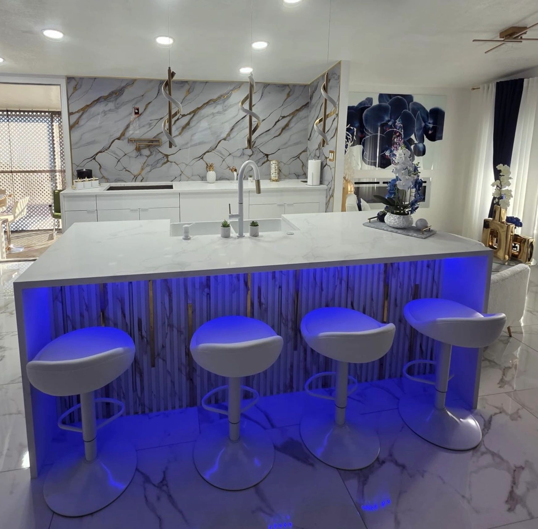 Modern kitchen island with blue LED lighting and white bar stools.