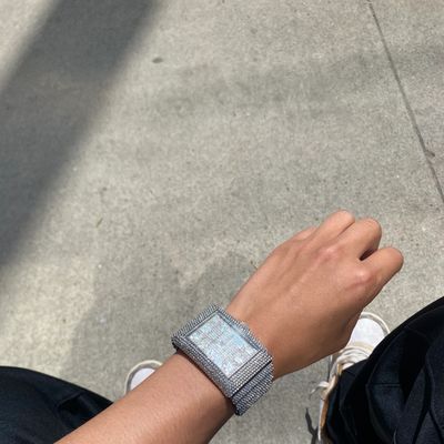 Wrist wearing a large, sparkling silver watch.