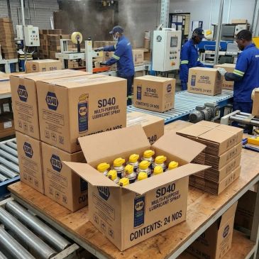Workers packing SD40 lubricant spray bottles in a factory.