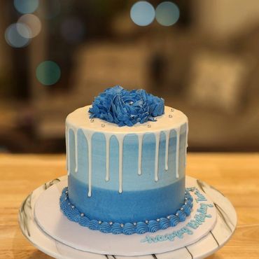 Blue ombre drip cake with a blue flower on top.