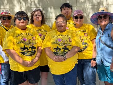 Group of volunteers in yellow shirts posing together outdoors.