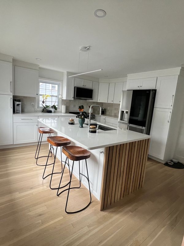 Modern kitchen with white cabinets and wooden bar stools.