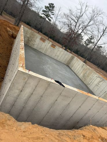 Concrete foundation walls forming a rectangular basement structure on a cleared plot.