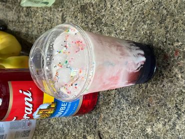 Colorful layered drink with ice and sprinkles in a clear cup.