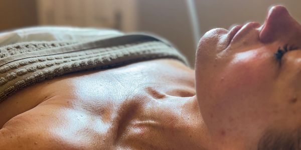 A woman lying down with eyes closed, bathed in soft light.