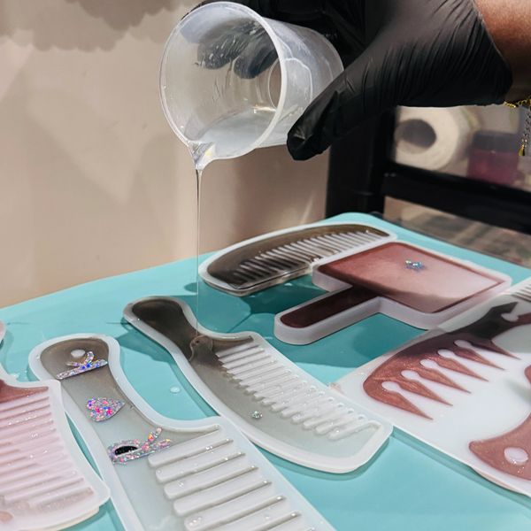Pouring resin into comb-shaped molds for crafting decorative items.