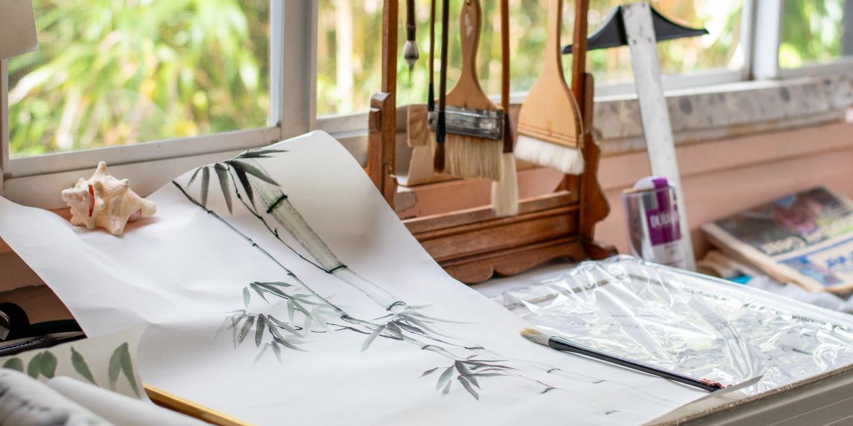 Painting workspace with brushes and bamboo art.