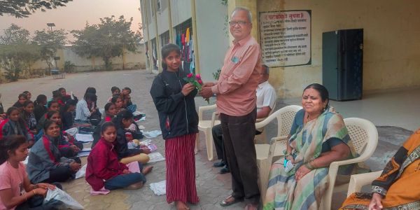 Man giving flower to girl at an outdoor gathering.
