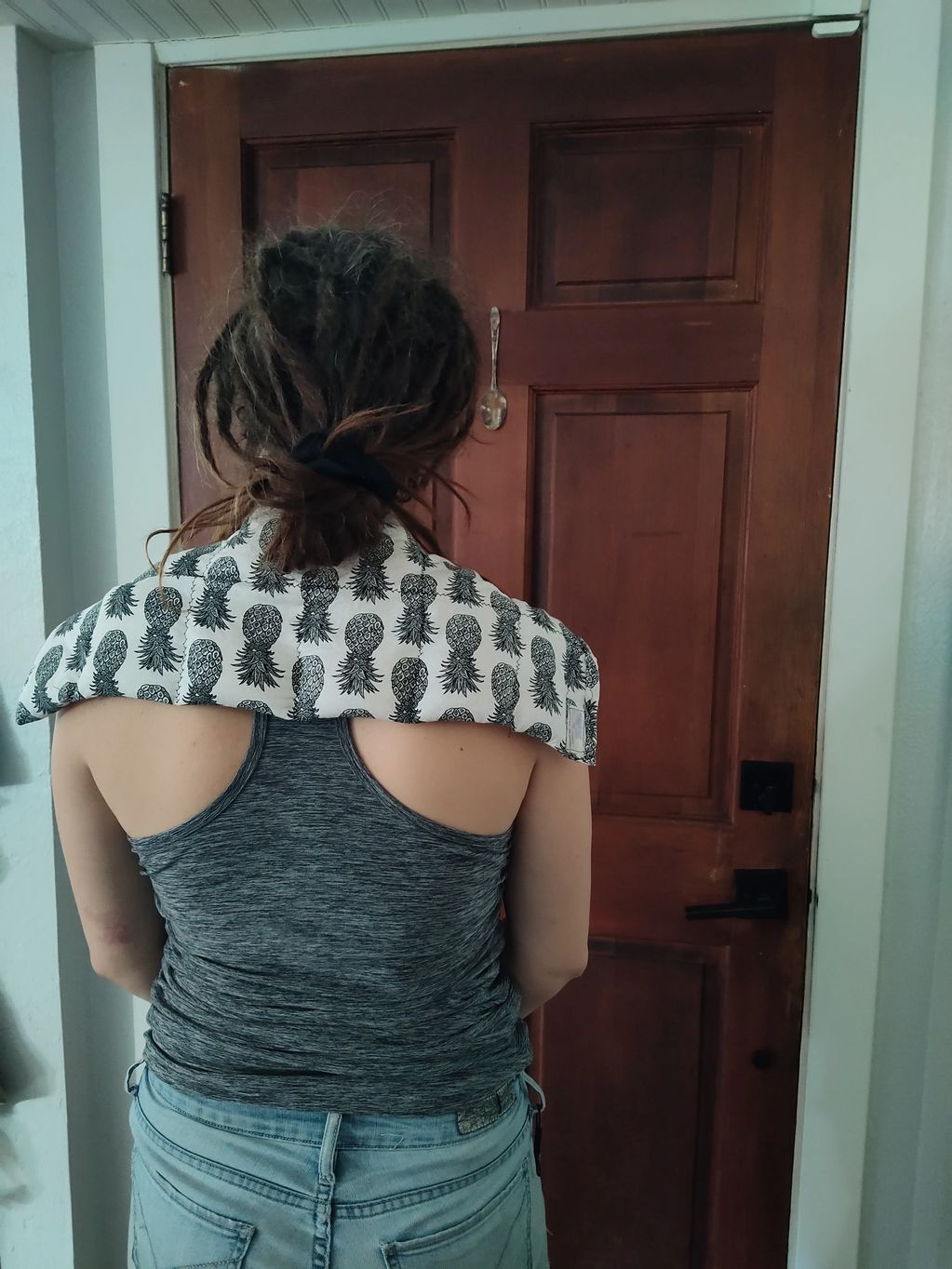 a woman standing facing a closed door with a salt pack on her shoulders