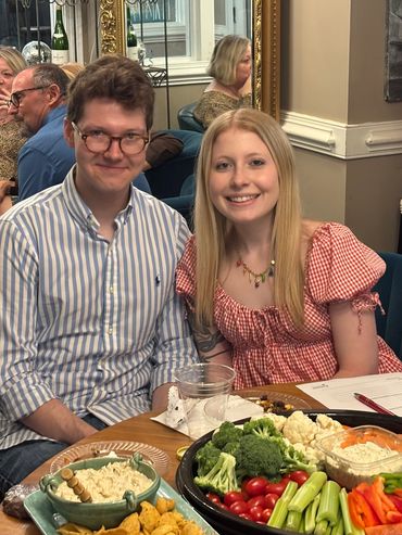 Young couple sitting at a table with a vegetable platter.