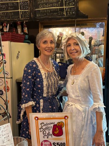 Two women in historical clothing posing indoors.