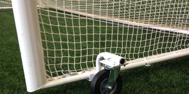 Close-up of a soccer goalpost wheel on artificial turf.