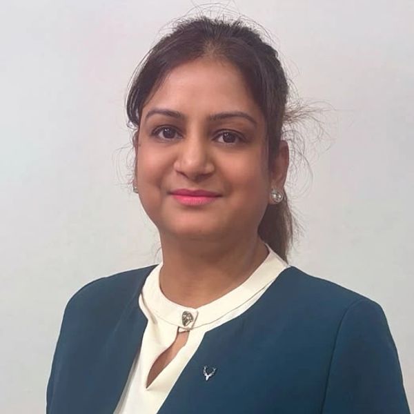 Woman in a teal blazer smiling indoors.