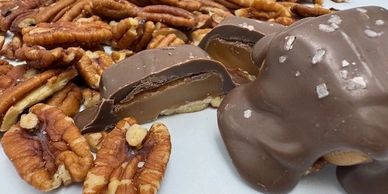 Chocolate-covered caramel candies with pecans and sea salt on a plate.