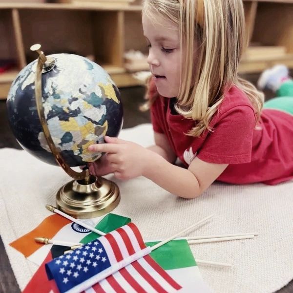 Young child finding the United States of America on the world globe. In a Montessori classroom